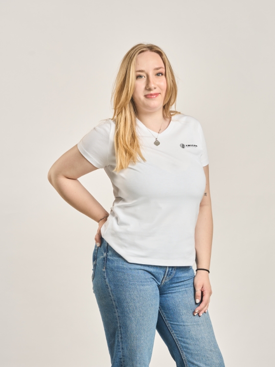 Model, lachend mit Jeans und mit weißem T-Shirt mit V-Ausschitt, mit schwarzem TRILUX Logo auf der Linken Brust